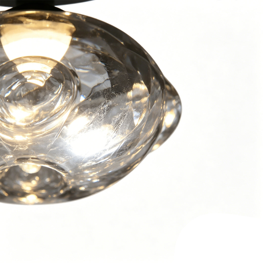 Close-up of glass shade on black wrought iron chandelier with warm lighting.