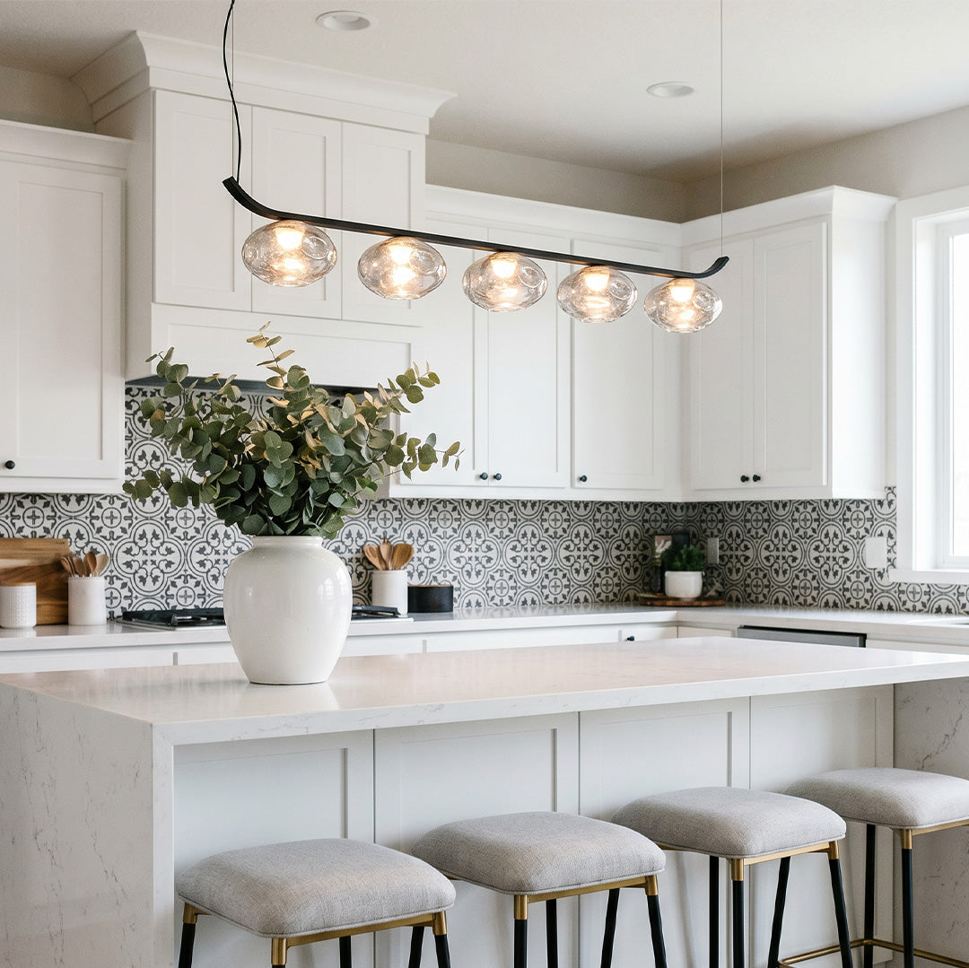 Linear black wrought iron chandelier installed over a kitchen island.