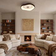 Bladeless fan with light mounted above a cozy living room with a fireplace, shelves, and curved sofas.
