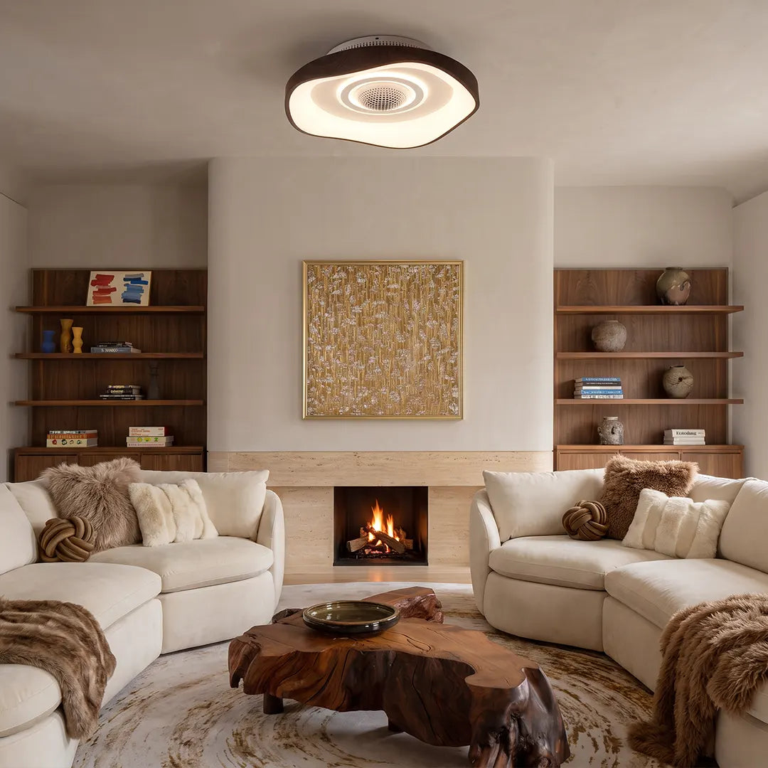 Bladeless fan with light mounted above a cozy living room with a fireplace, shelves, and curved sofas.