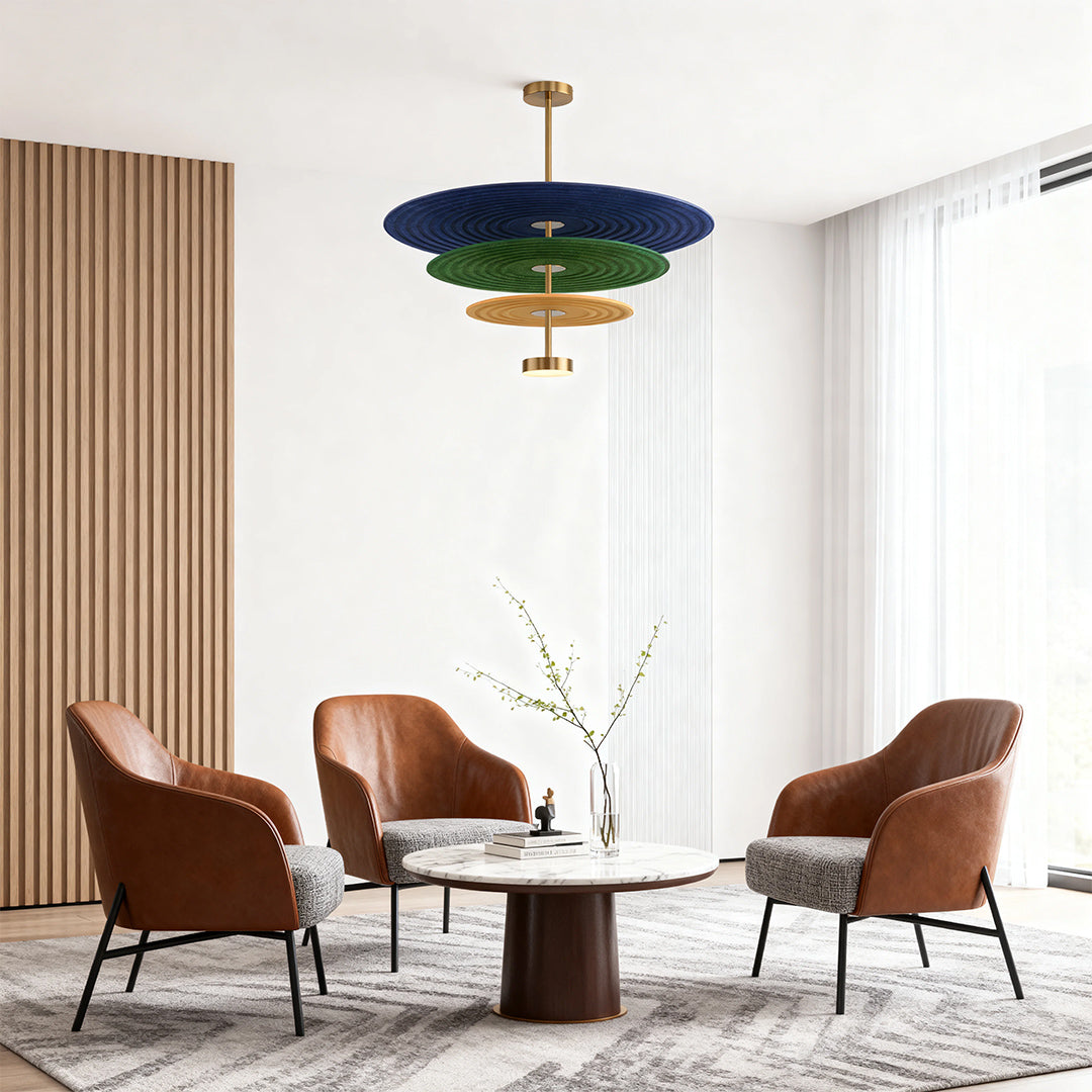 A striking blue and green 3 tier chandelier serving as a central decorative light fixture in a modern lounge area with armchairs.