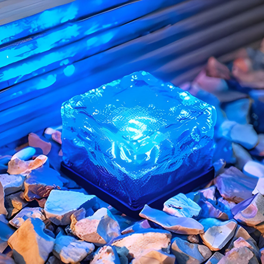 Blue illuminated ice cube outdoor light on rocks for landscape decoration.