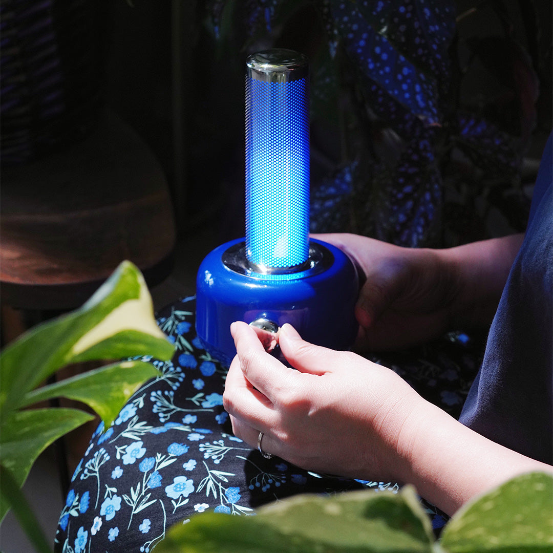 Blue industrial metal USB rechargeable table lamp held in hand demonstrating portable design