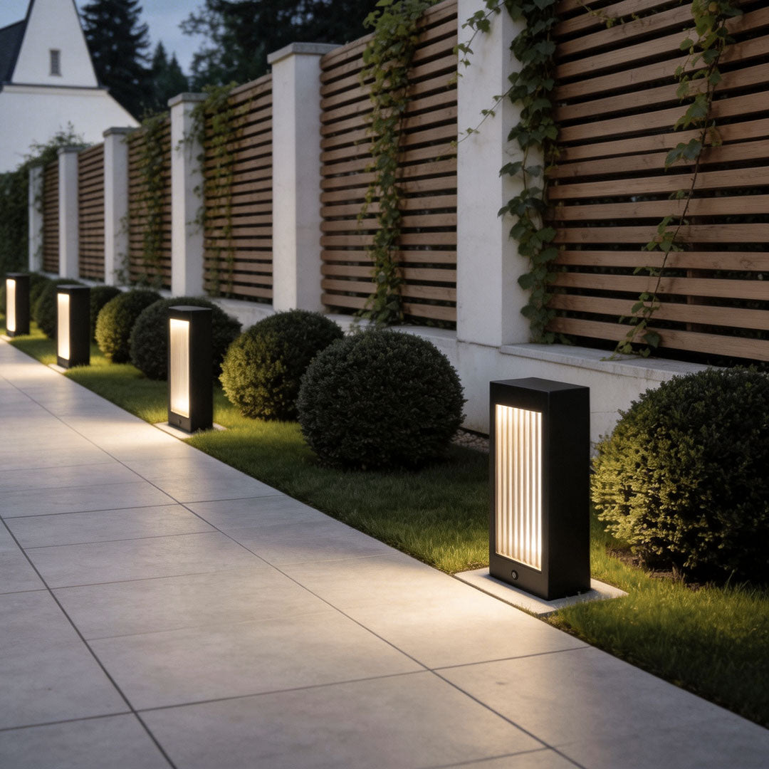 Bollard garden lights with a rectangular design, providing illumination along a fence.