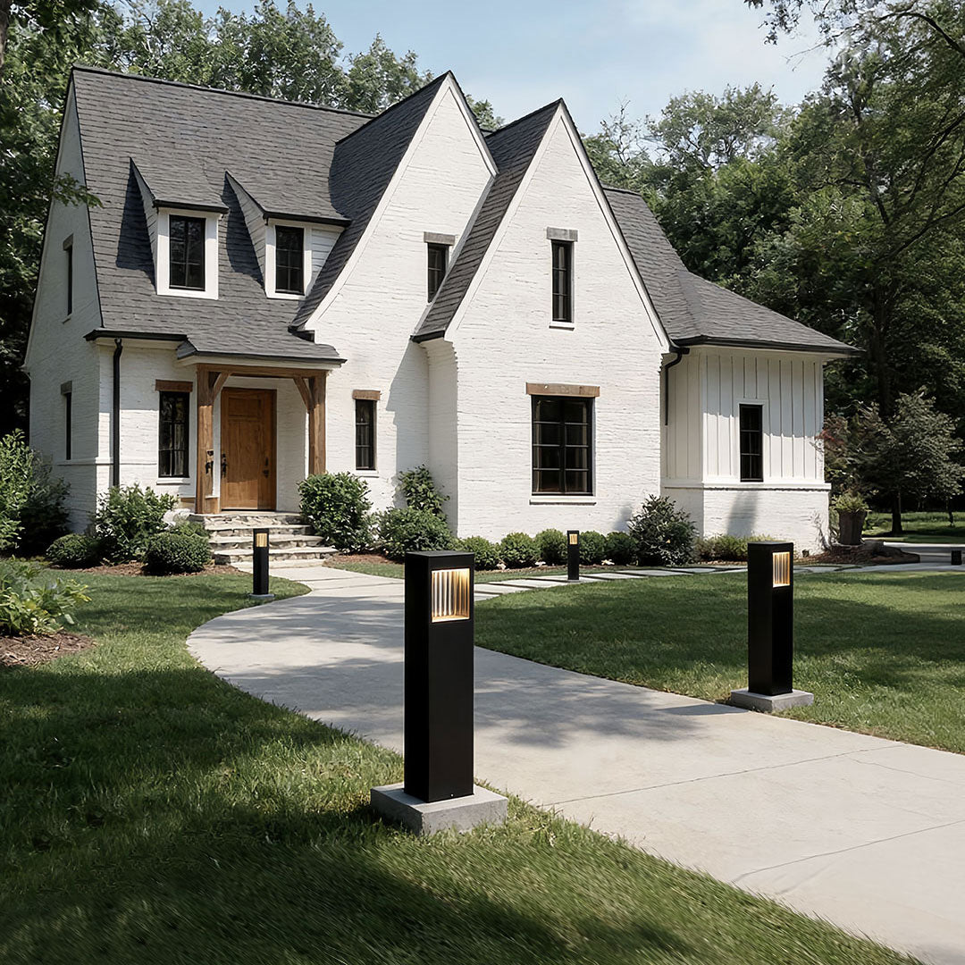 Bollard garden lights with a sleek design, enhancing a garden walkway near a house.