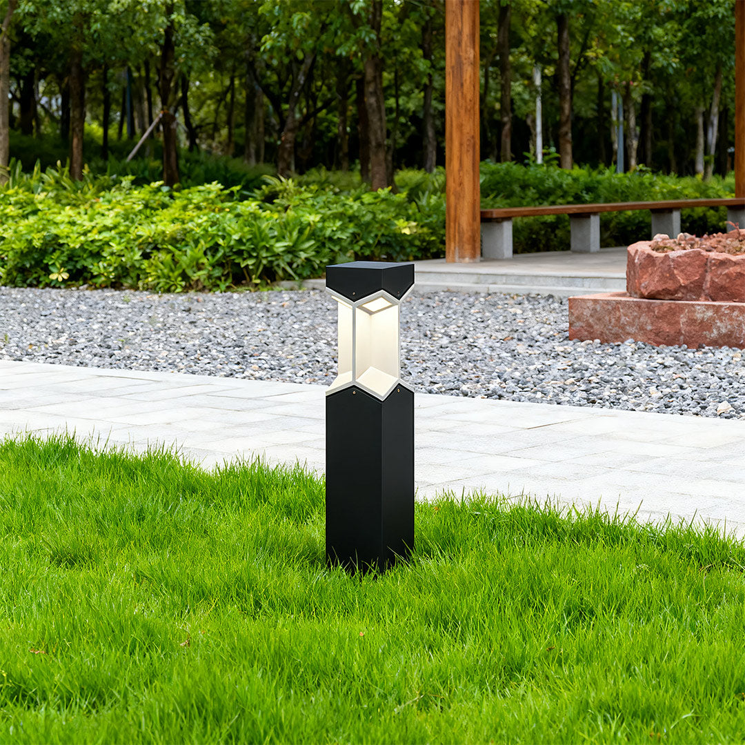 Bollard landscape light in a garden with flowers, adding a decorative and functional glow.