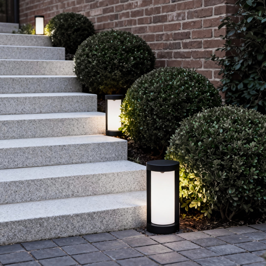 Bollard landscape light with a minimalist design, installed near stone steps for elegant outdoor lighting.