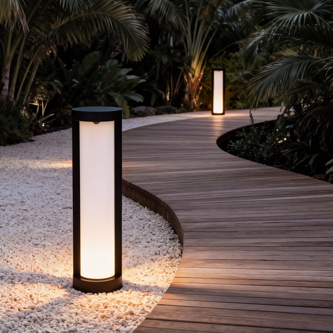 Bollard landscape light with a sleek cylindrical design, illuminating a curved garden pathway at night.