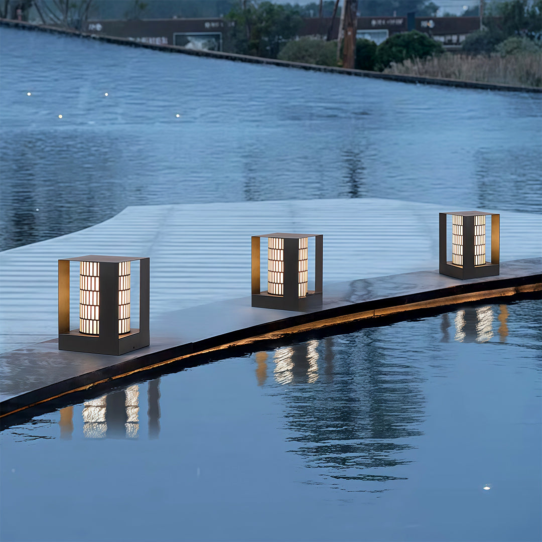 Modern bollard landscape lights placed along a waterfront walkway, creating beautiful night reflections.