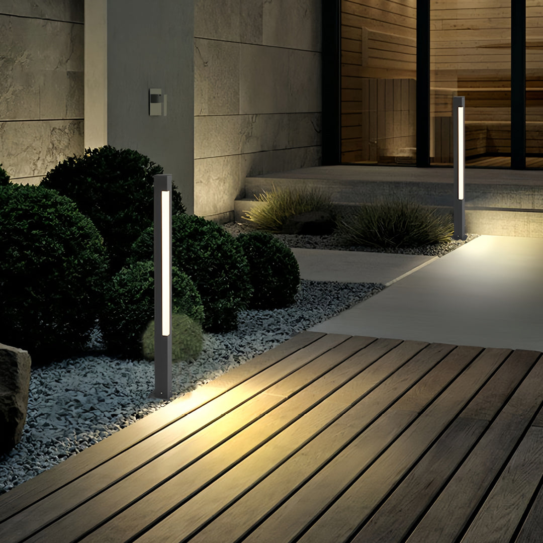 Contemporary bollard landscape lighting illuminating a wooden deck pathway in a residential outdoor space.