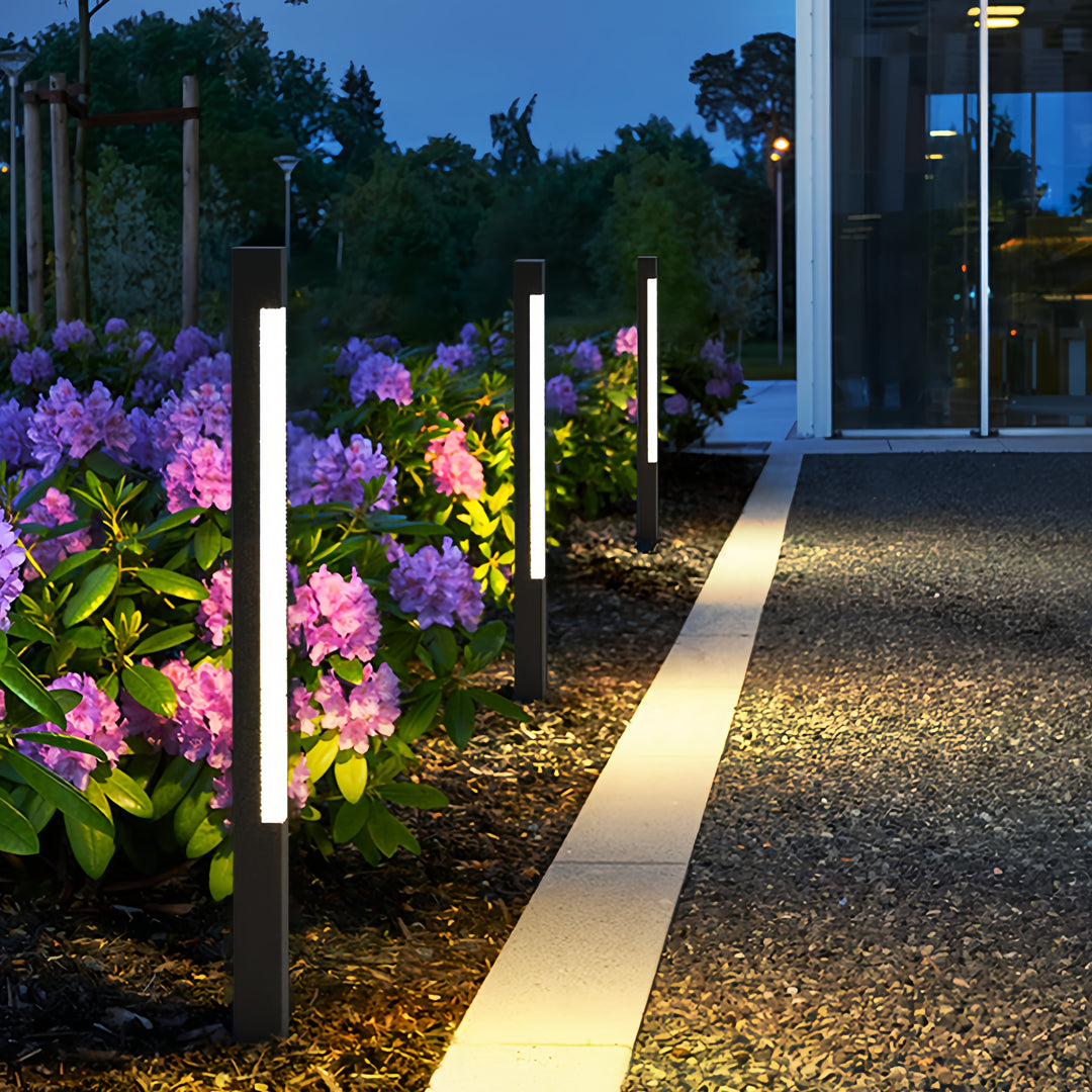 Bright bollard landscape lighting lining a flower-filled garden path creating vibrant evening ambiance.