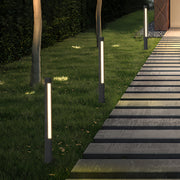 Multiple slim bollard landscape lighting fixtures installed along a garden walkway for subtle night illumination.