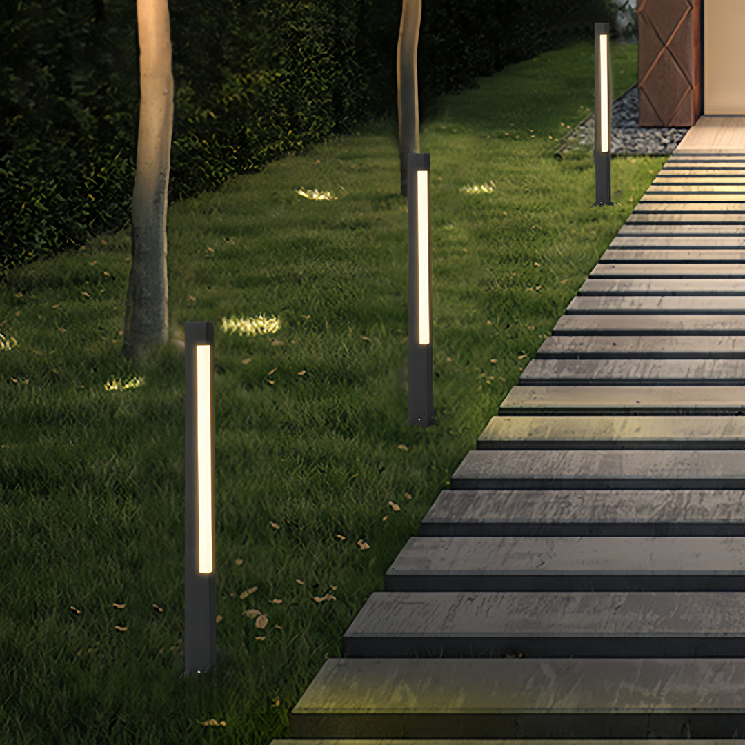 Multiple slim bollard landscape lighting fixtures installed along a garden walkway for subtle night illumination.
