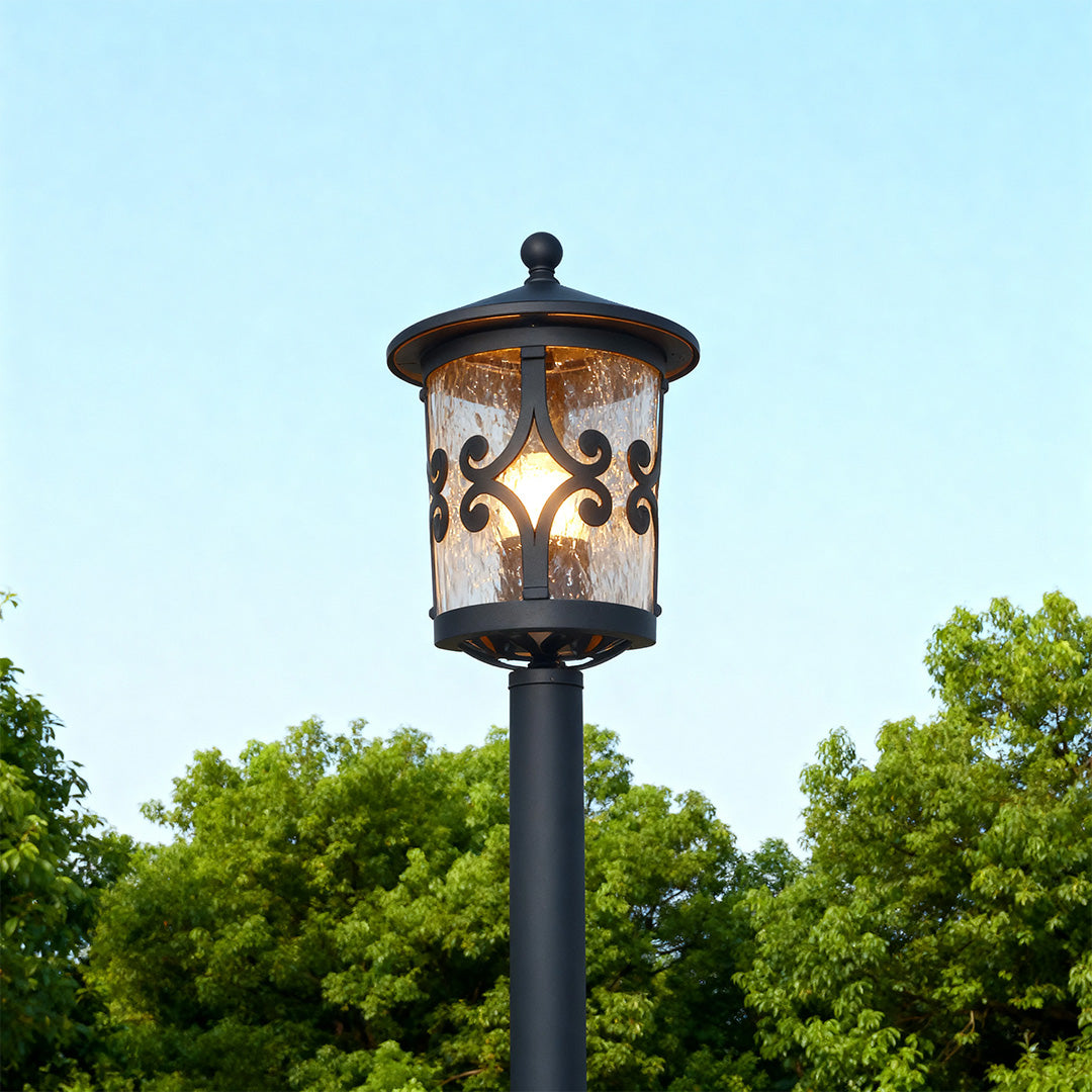 Bollard LED light standing prominently on green lawn against clear blue sky with tree backdrop