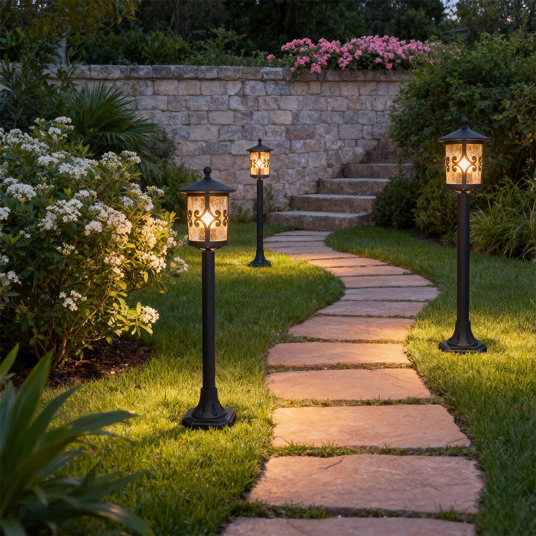 Multiple bollard LED lights lining stone paver walkway through landscaped garden at twilight