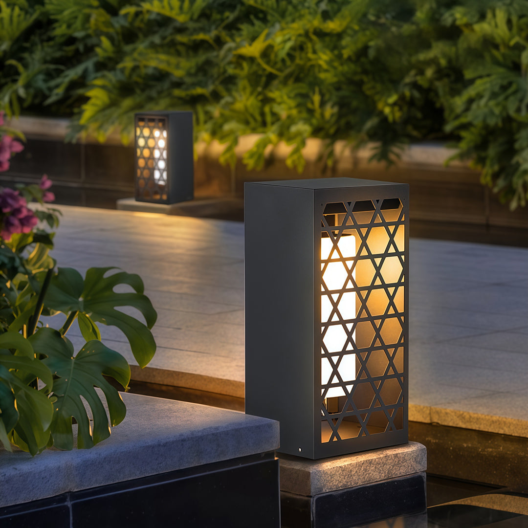 Bollard light fixtures installed along a garden, offering geometric patterns that complement modern landscaping.