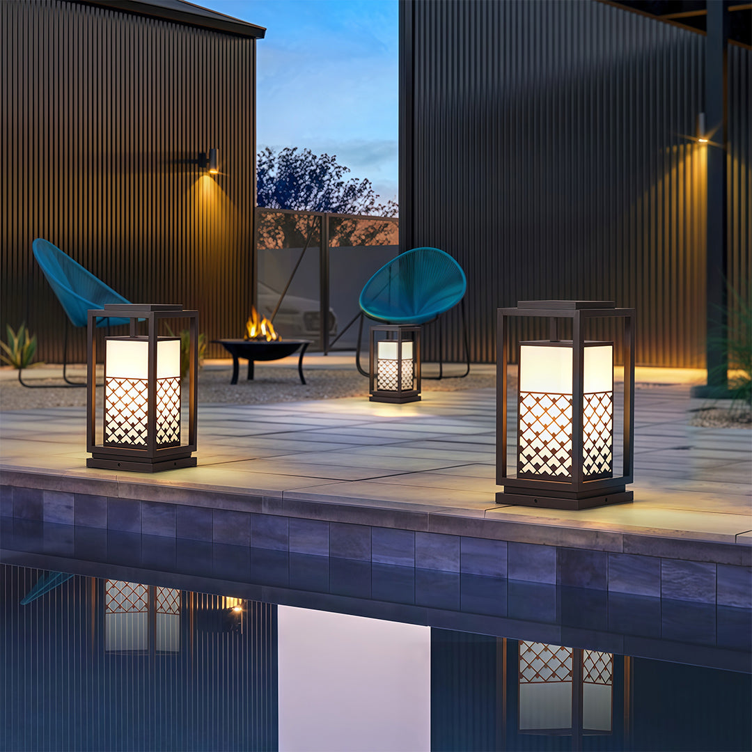 Bollard light fixture with geometric lattice pattern, placed along the edge of a water feature to enhance the scenery.