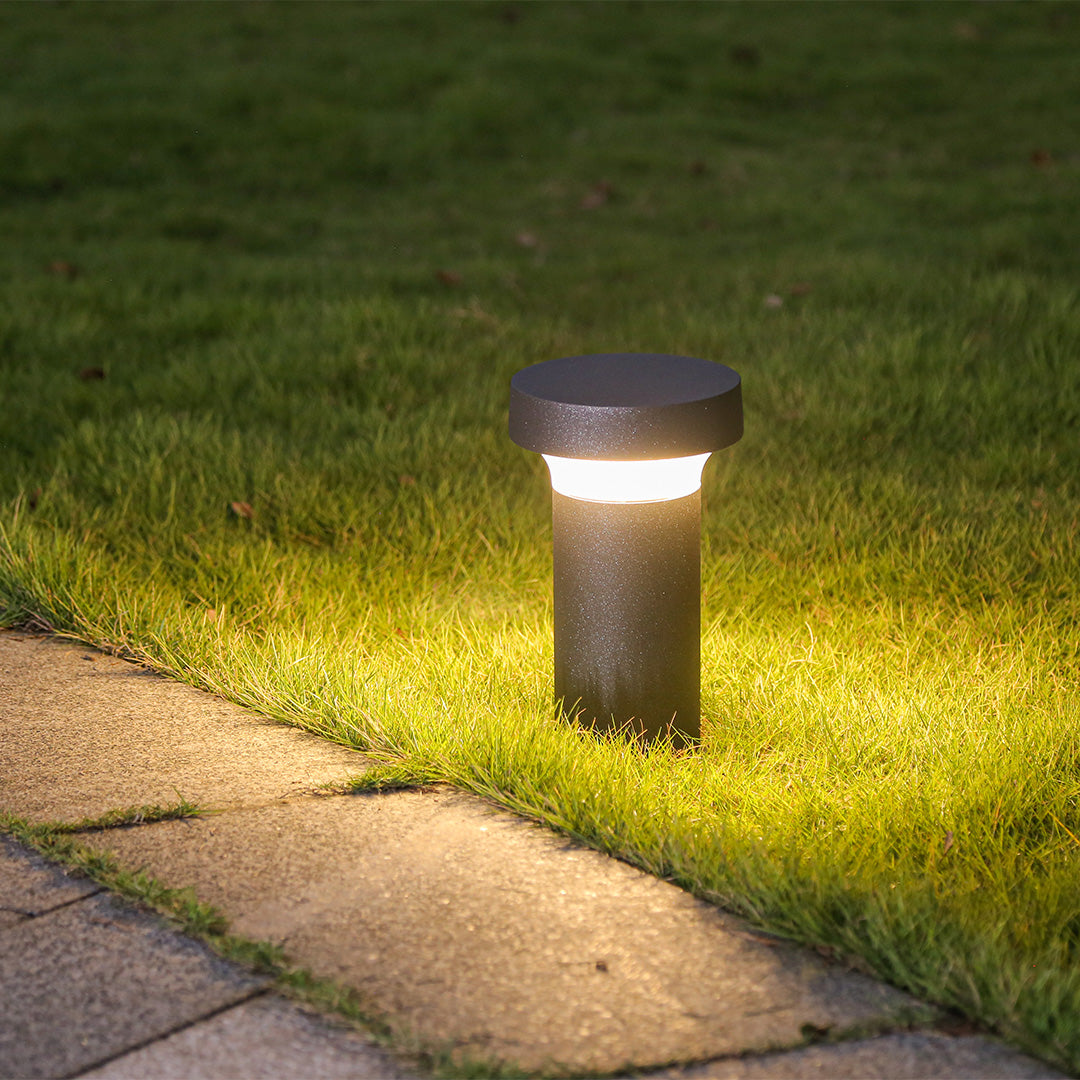 Contemporary outdoor light fixture casting warm glow on lawn area at night