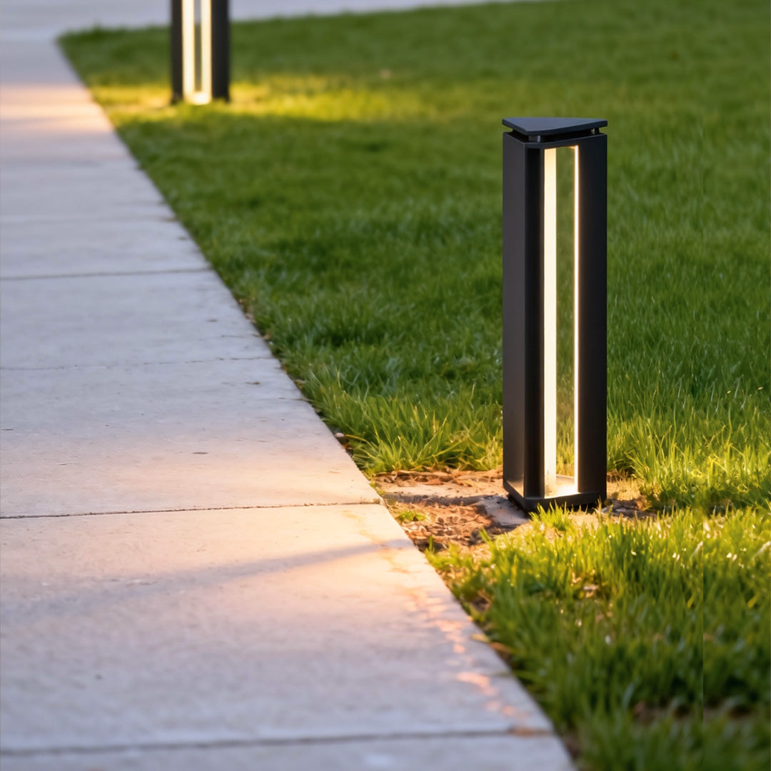 Sleek bollard outdoor lights lining a concrete pathway with warm directional lighting during dusk.