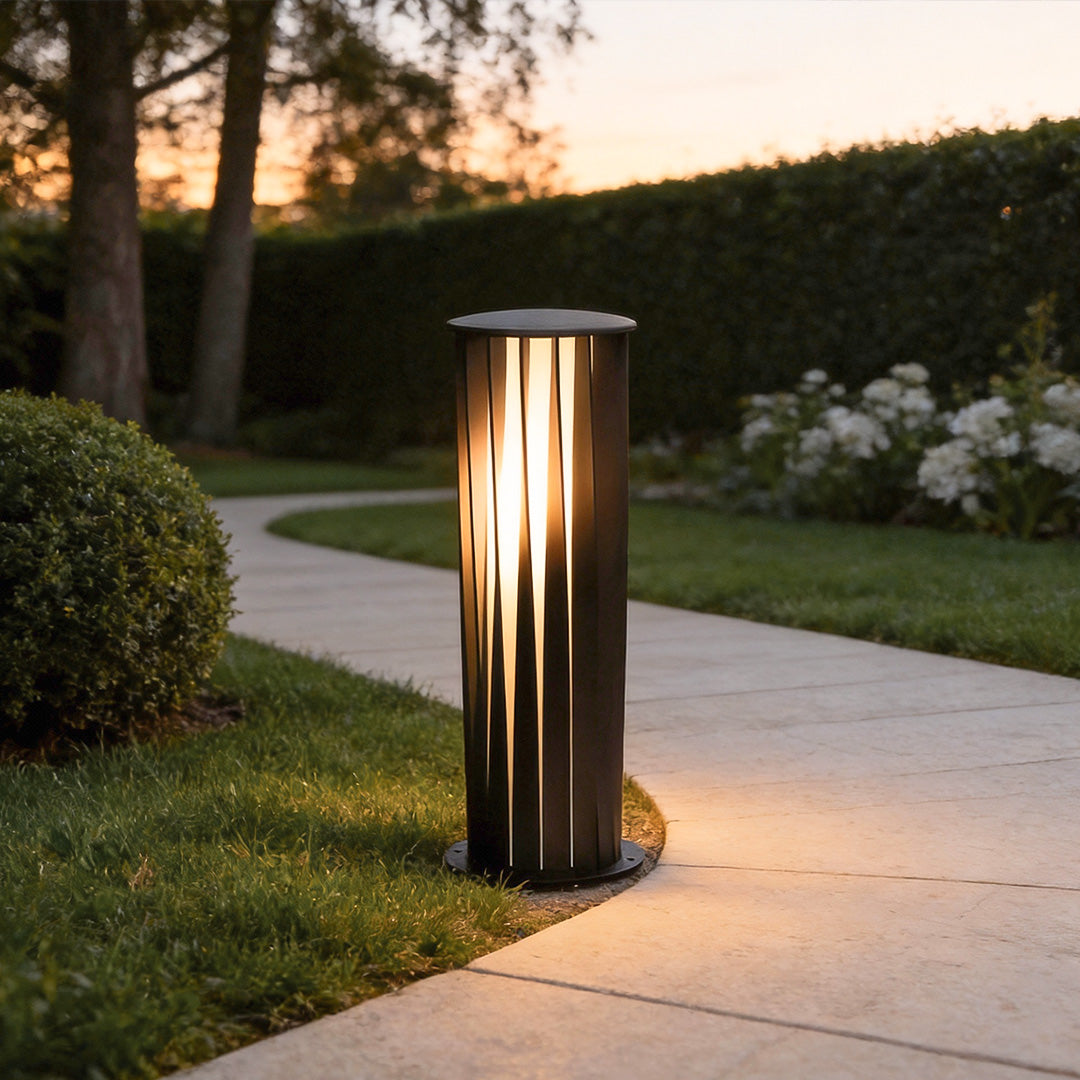 Bollard path light installed beside a curved garden walkway providing warm guidance lighting.
