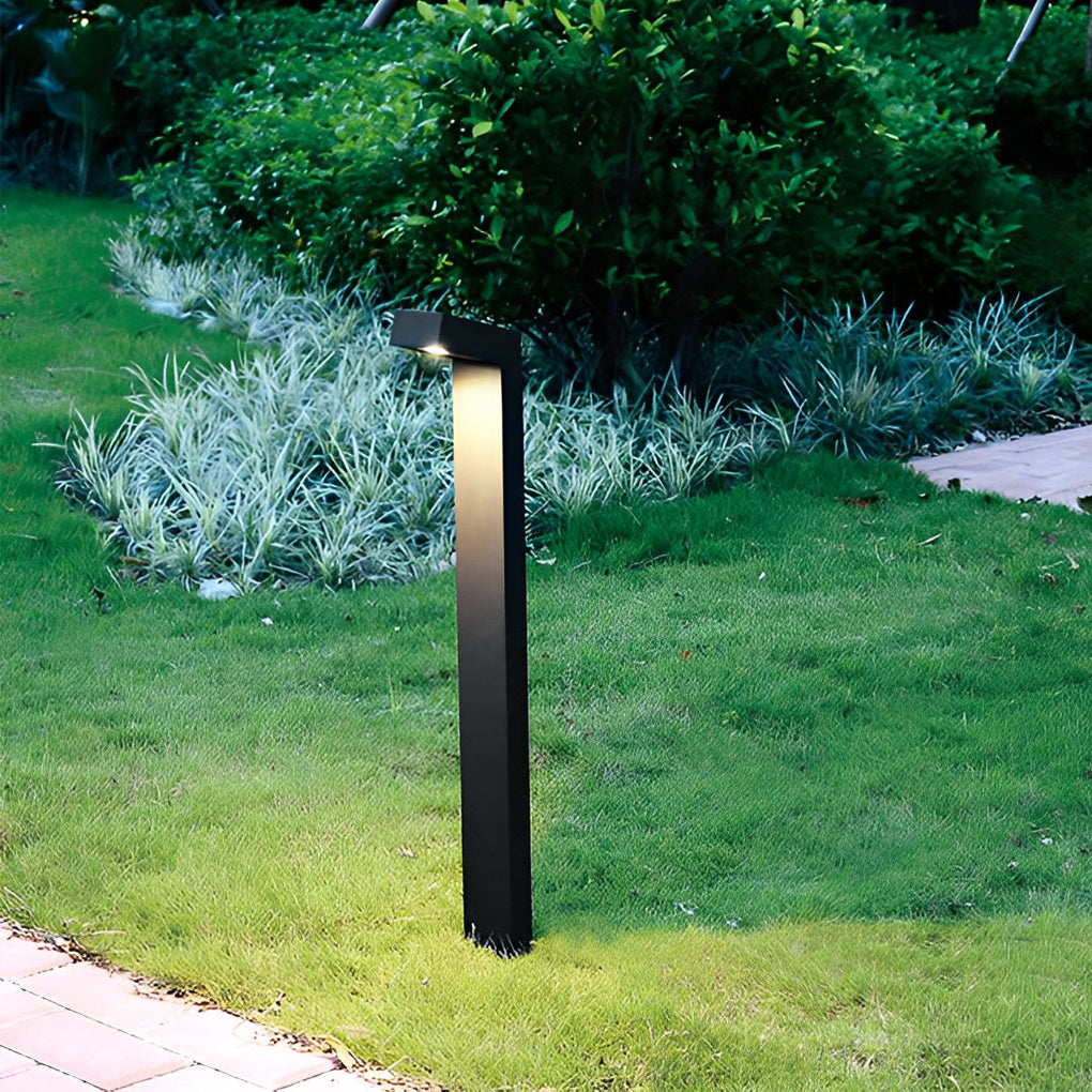 Bollard path light casting a soft glow on a grassy area, perfect for garden pathways.