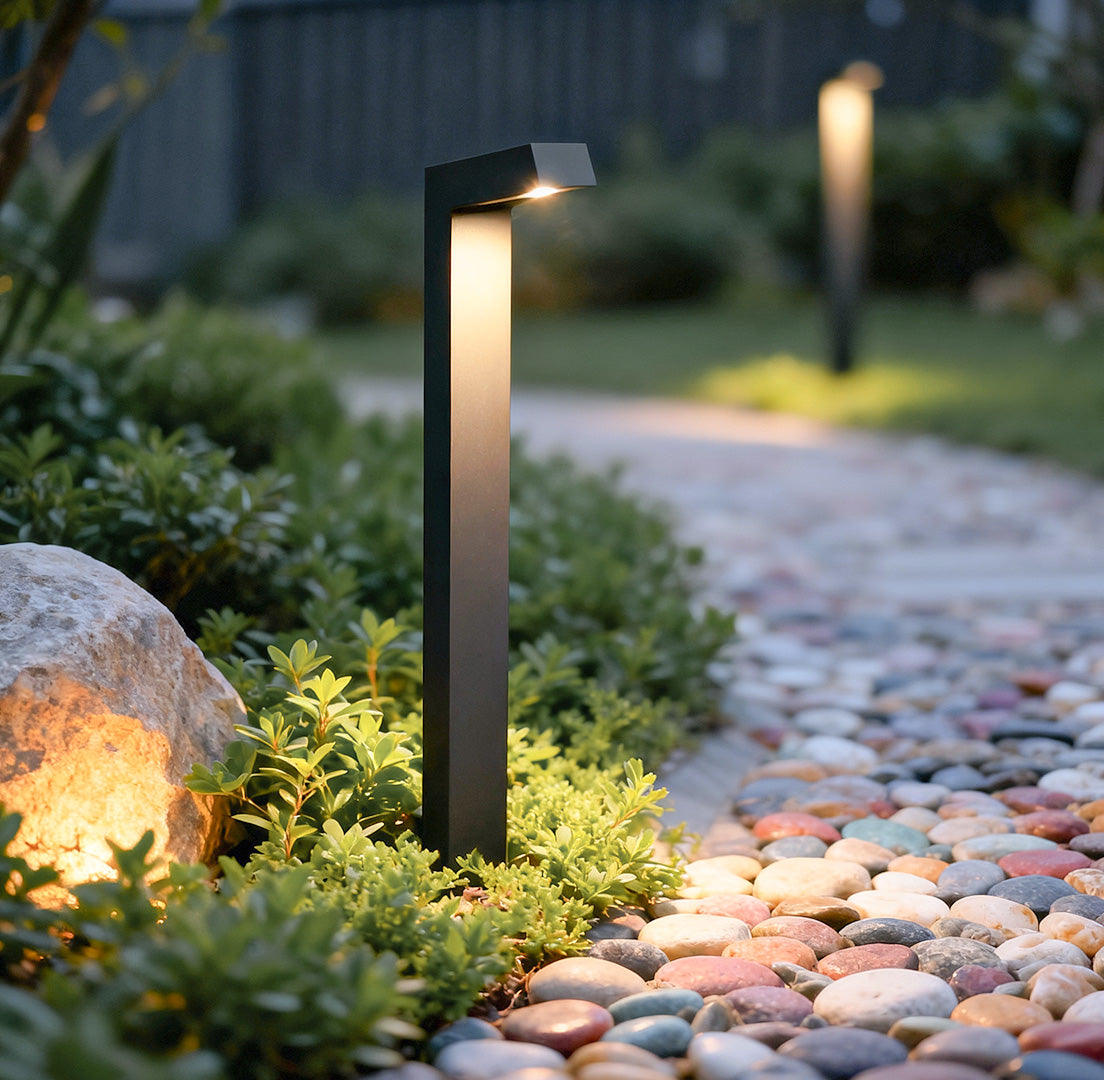 Bollard path light installed along a stone pathway, enhancing the landscape with warm illumination.