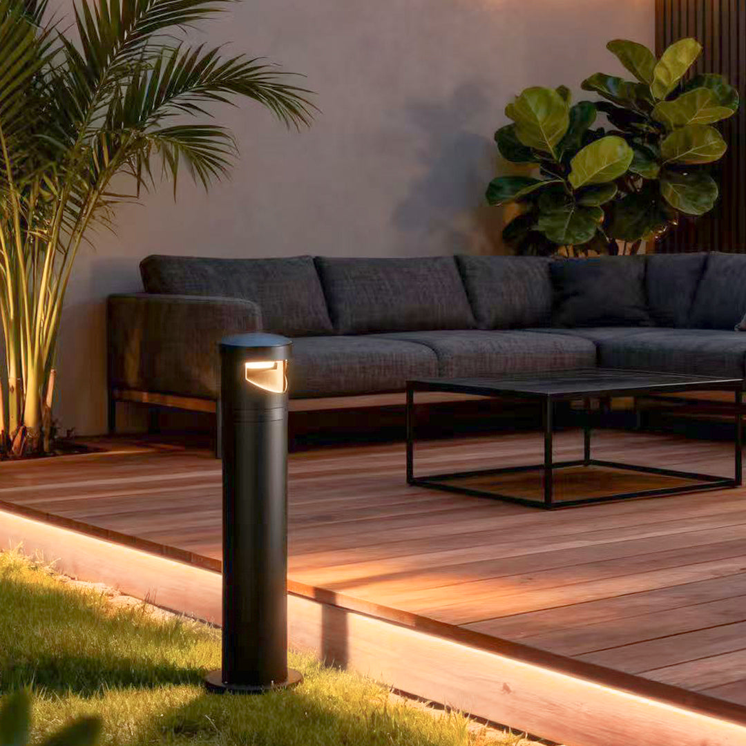 Bollard pathway lights providing accent lighting for outdoor patio seating area with contemporary furniture at dusk