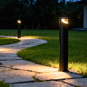Bollard pathway lights illuminating stone walkway at night creating warm ambient glow along garden path