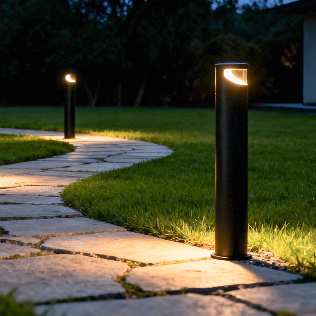 Bollard pathway lights illuminating stone walkway at night creating warm ambient glow along garden path