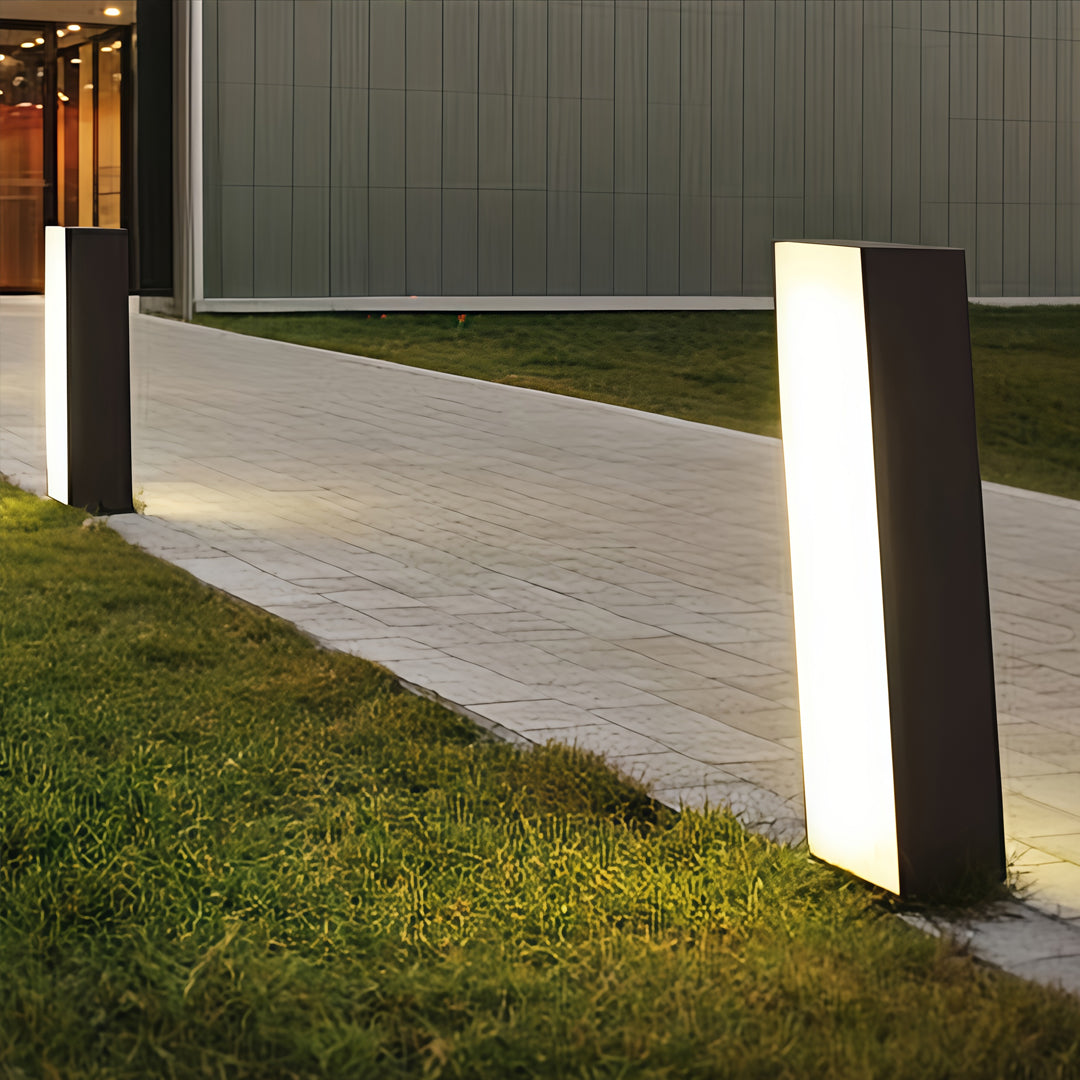 Tall rectangular bollards with lighting installed along a concrete pathway for modern outdoor illumination.