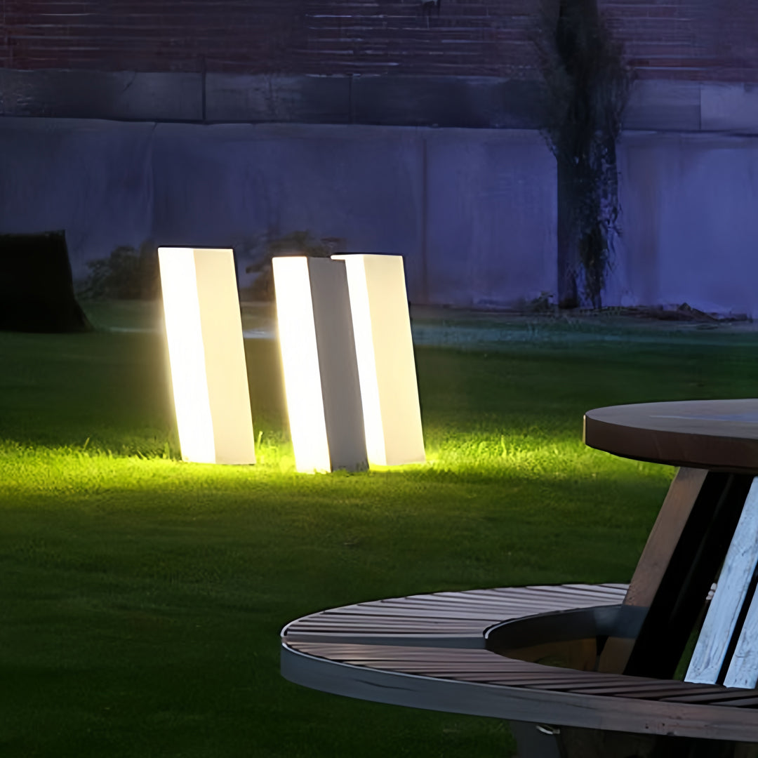 Bright glowing bollards with lighting arranged beside a walkway, adding soft illumination to the landscape.