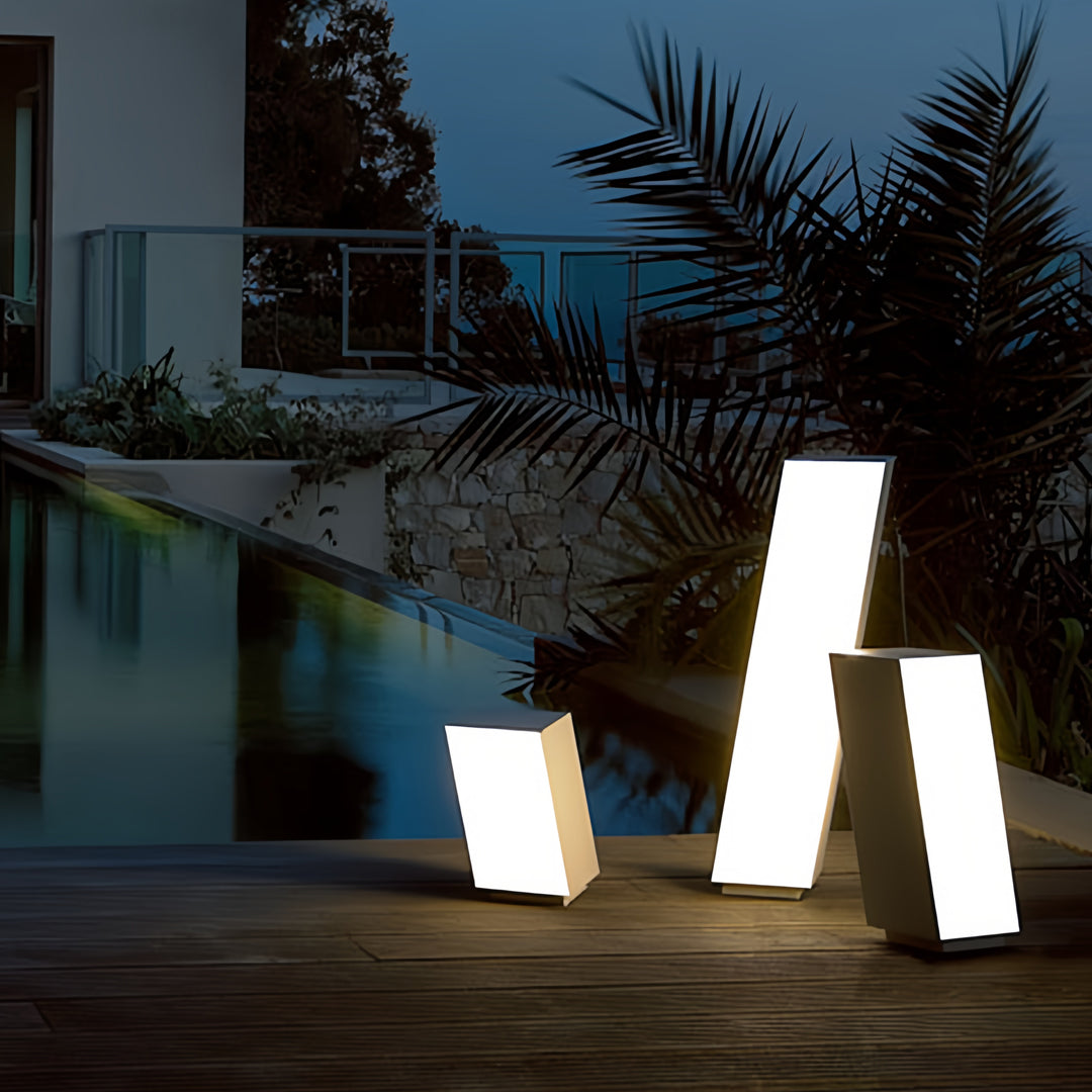 Outdoor bollards with lighting illuminating a pathway beside water, creating a warm ambient effect at night.