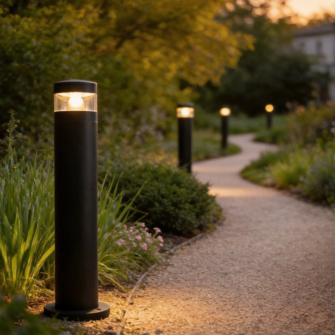 Bollards with lights lining a curved garden path with soft landscape illumination at night.