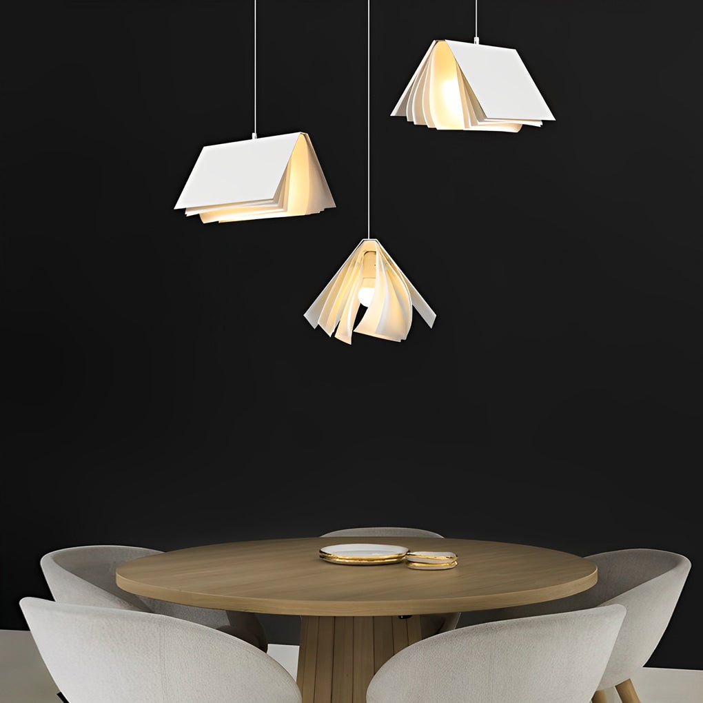 Minimalist book pendant light cluster above a round dining table, showcasing artistic folded pages design in a modern interior.