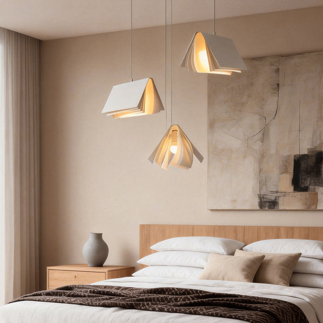 Modern book pendant light hanging above a cozy bedroom, featuring folded book-inspired panels with warm ambient glow.
