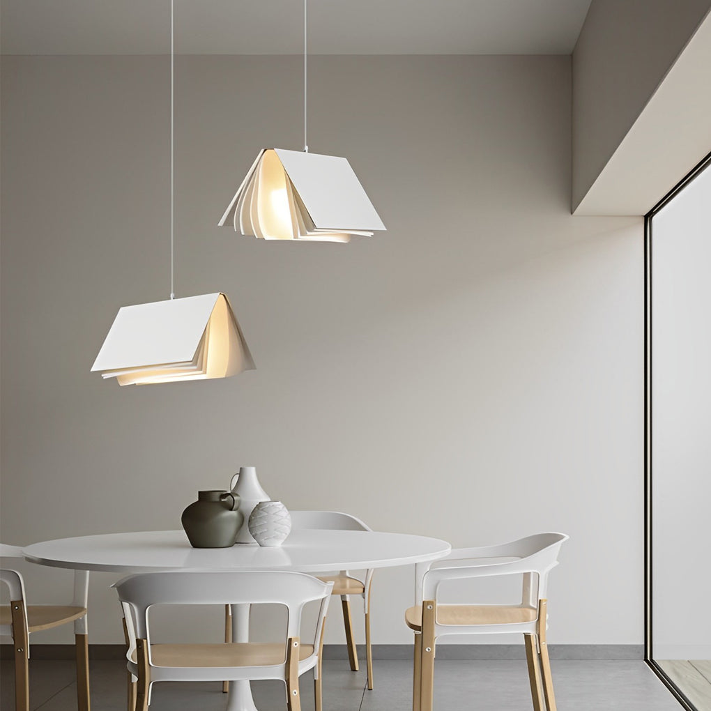Modern book pendant light above a dining table, blending clean lines and folded book aesthetics in a bright interior.