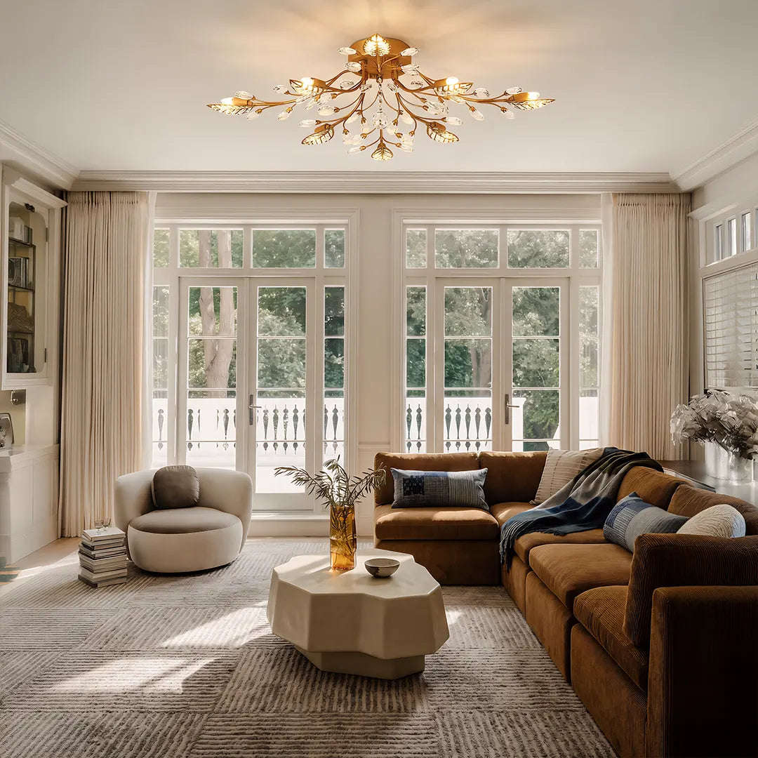 Modern branch chandelier in a bright living room with large windows, brown sofa, and light rug.