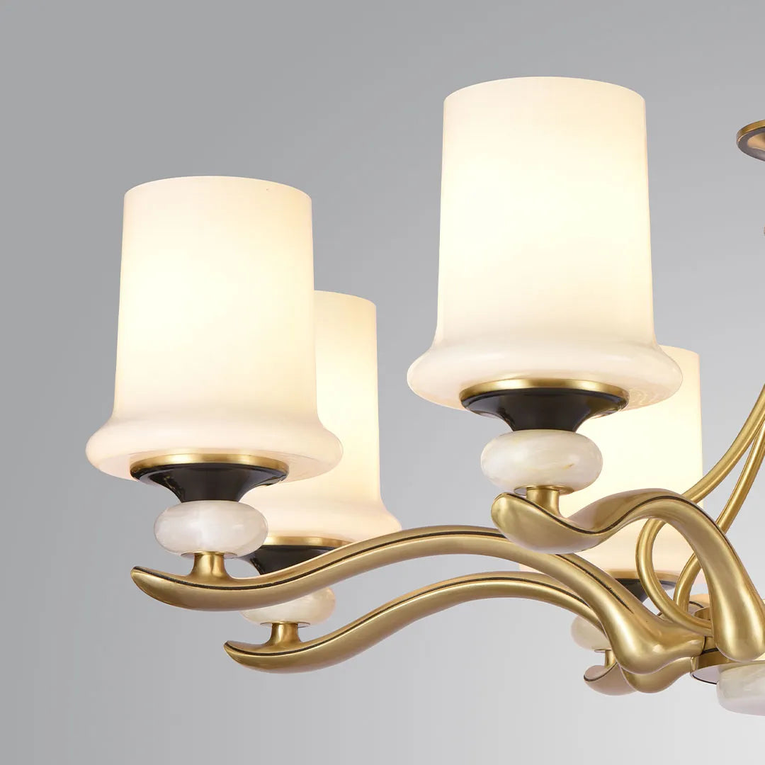 Close-up of brass candle chandelier showing curved brass arms and elegant white glass shades.