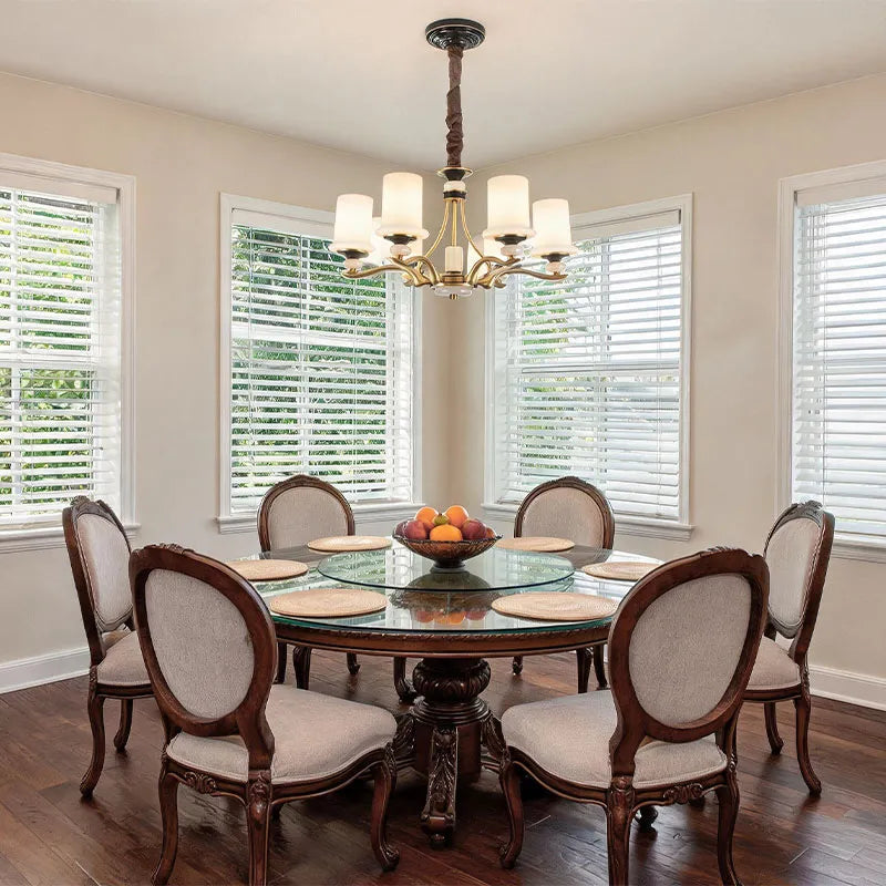 Brass candle chandelier installed above a dining table with a traditional elegant interior design.