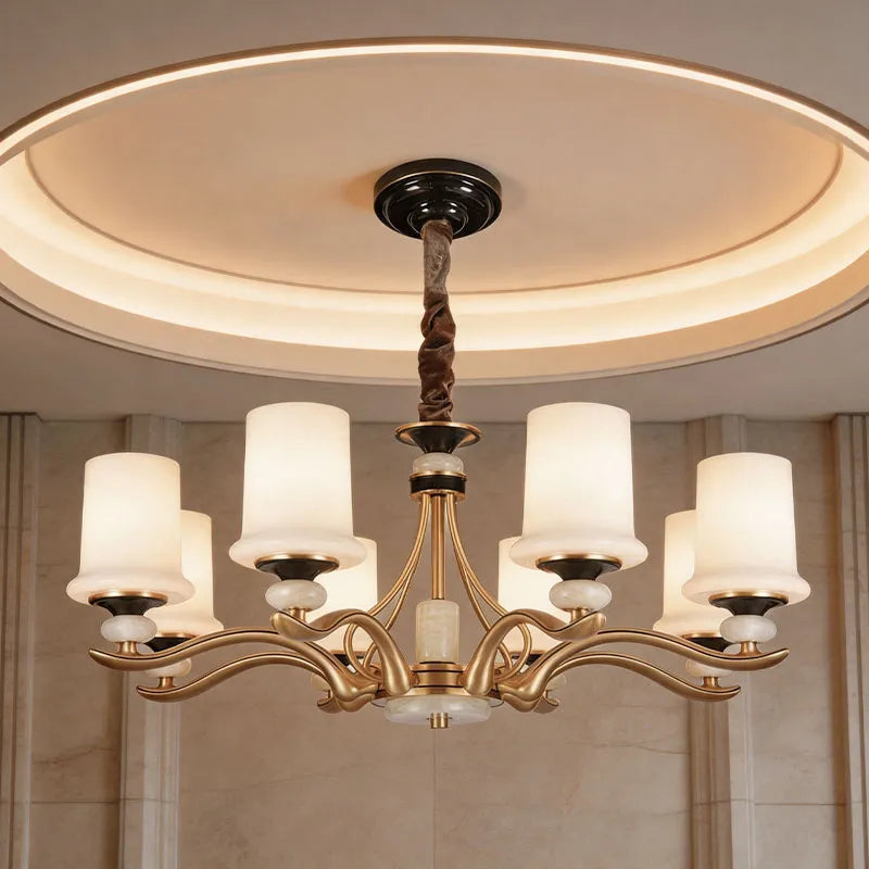 Brass candle chandelier with white shades installed in a modern dining room with elegant ambient lighting.