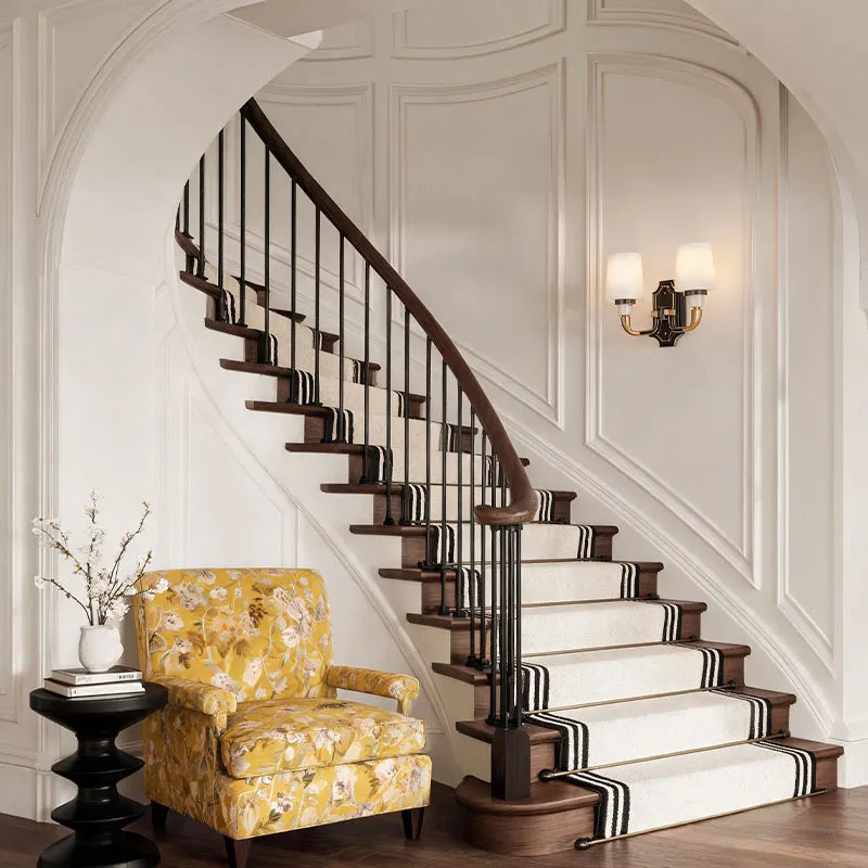 Brass candle sconces wall mounted beside a staircase creating a sophisticated home atmosphere.