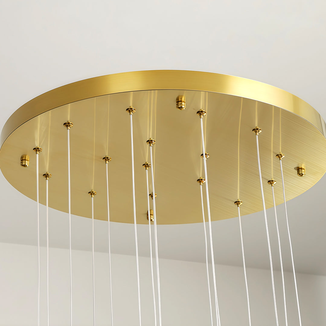 Ceiling mount plate of a modern brass chandelier with multiple hanging lights.