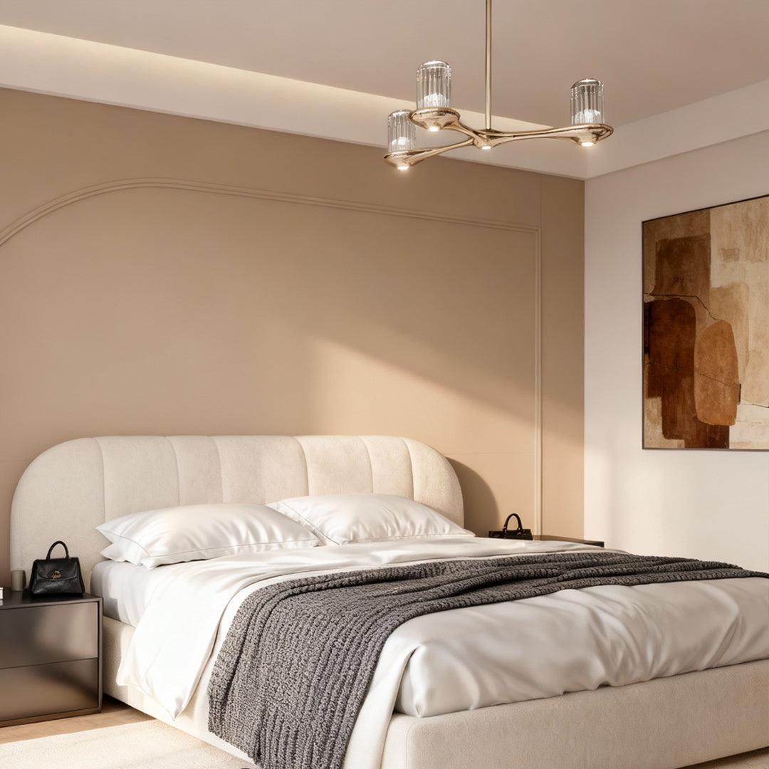 Brass crystal chandelier creating ambient glow in cozy bedroom corner with neutral color palette and soft bedding