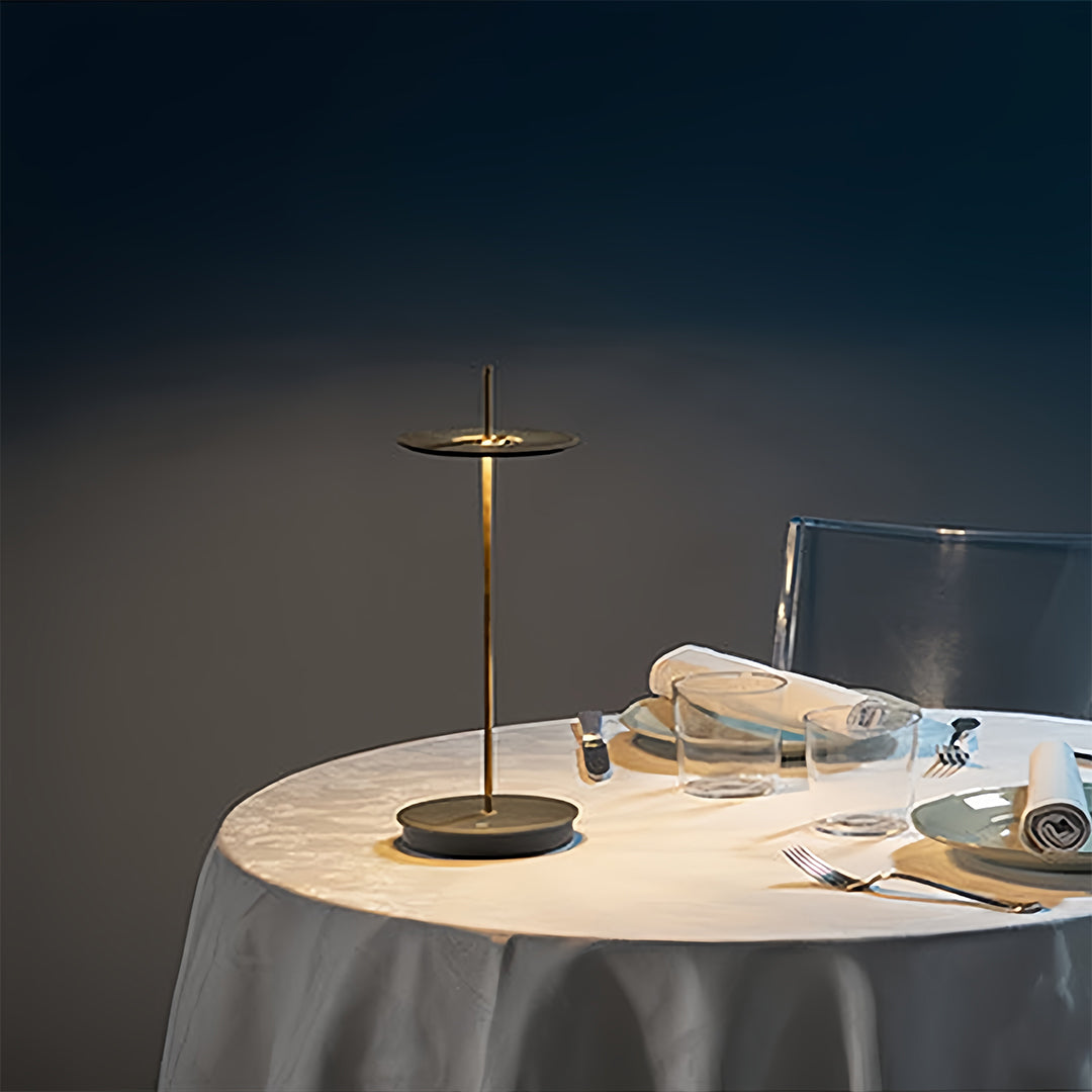 Brass dimmable table lamp illuminating elegant dining table with white tablecloth and dinnerware