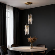 Brass glass pendant light providing ambient lighting in dark contemporary room above round table.