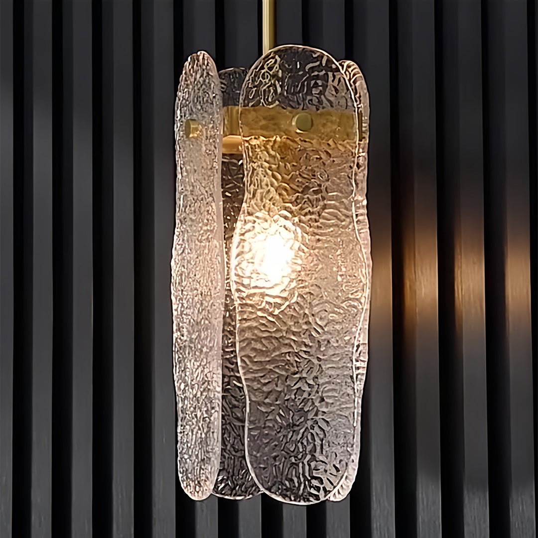 Brass glass pendant light creating dramatic effect against black curtains with warm interior glow.