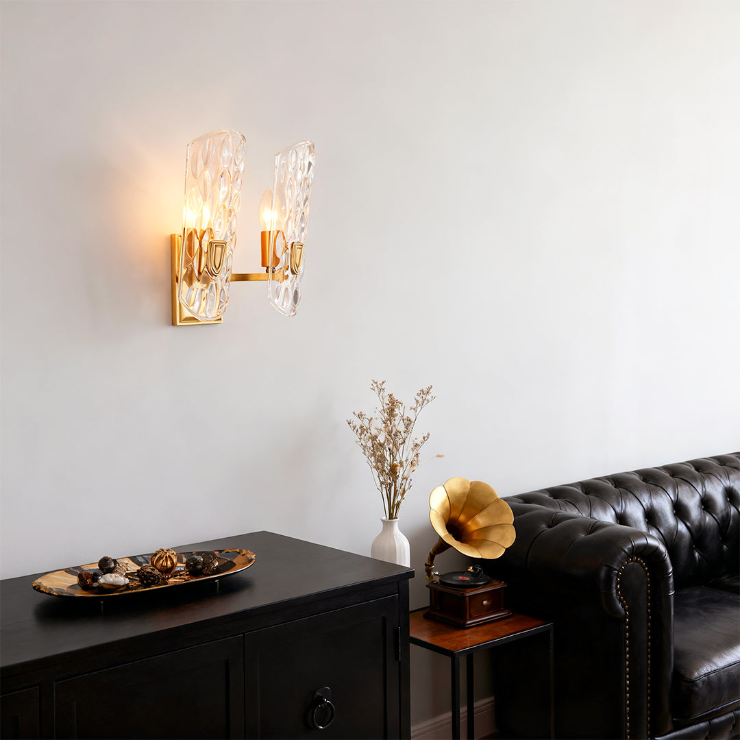 Brass glass wall light providing elegant lighting in contemporary space with black sofa