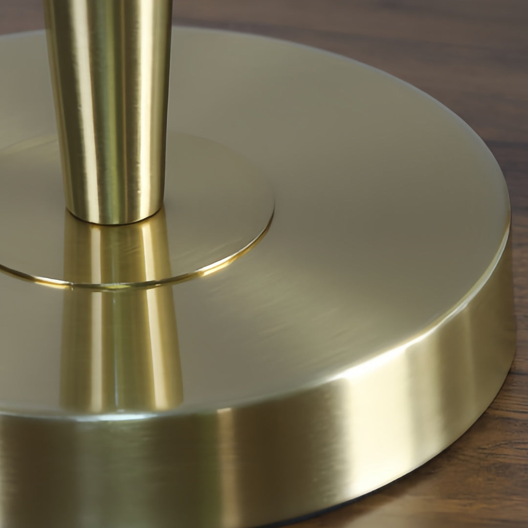 Close-up detail of modern brass table lamp base showing smooth metallic construction