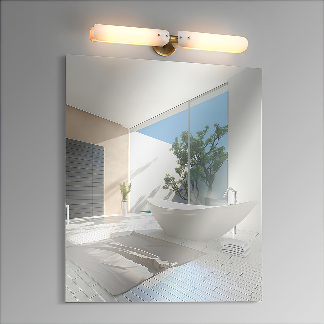 Brass wall light with glass shade providing task lighting above modern bathroom vanity and mirror.