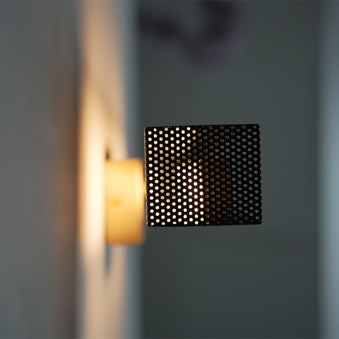 Brass wall light mounted on white wall, showcasing minimalist geometric style.